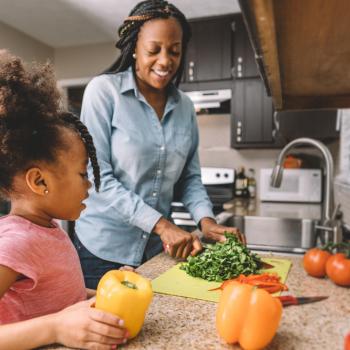 Mãe e filha na cozinha preparando refeição com alimentos ricos em ferro