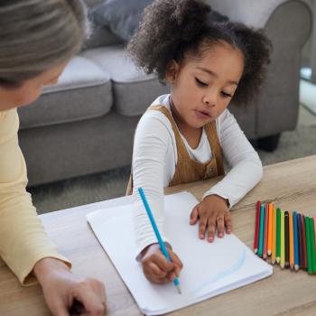 Mulher adulta ensinando uma garotinha a colorir/ desenhar, essa é uma atividade que estimula o desenvolvimento neuropsicomotor