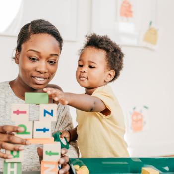 Mulher com um garotinho brincando de empilhar cubinhos educativos