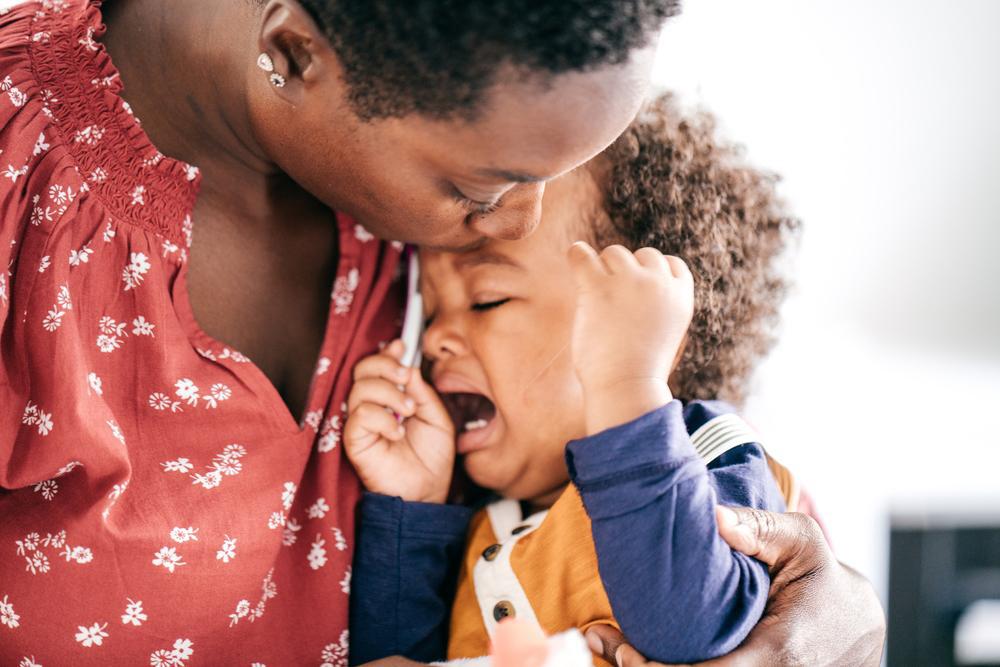 Mãe consola o filho que chora e faz birra em seu colo.