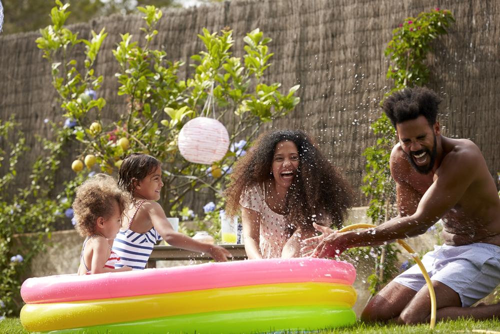 Foto de uma família se divertindo em um ambiente aberto com uma piscina de plástico colorida