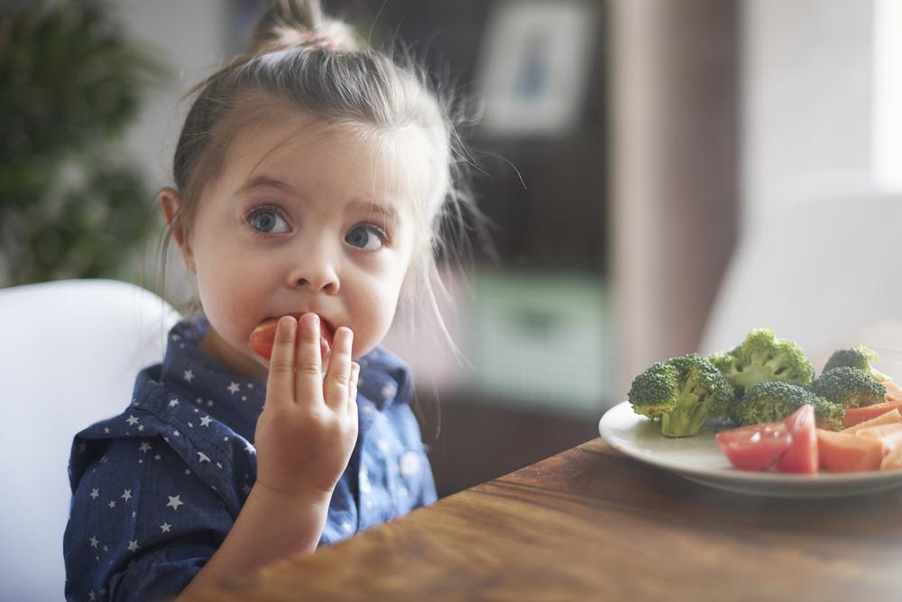 Foto de uma menina comendo verduras 